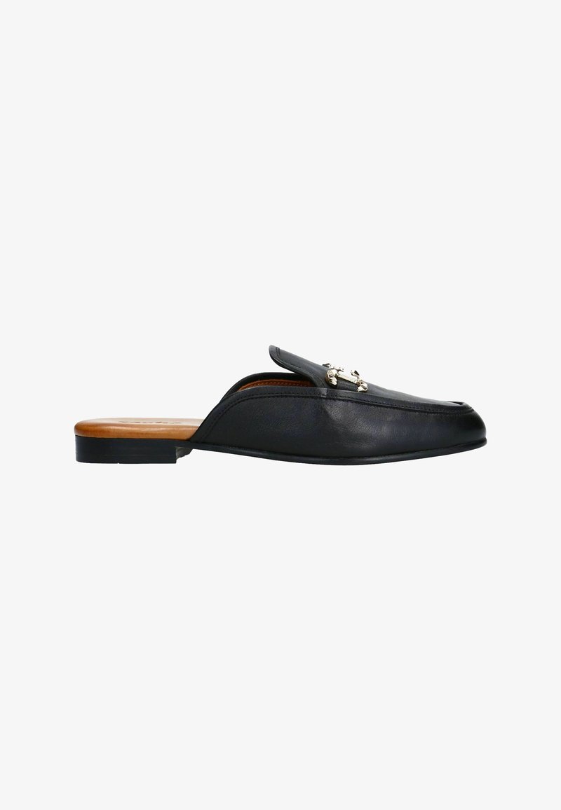 Chaussure slip-on en cuir noir avec un bout pointu, semelle plate et accessoire en métal argenté décoratif sur le dessus. Texture lisse et design minimal.
