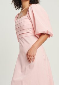 Valkoinen midi-mekko neliön muotoisella kaula-aukolla, pleatatuilla rinnoilla ja puffihihnoilla. Sileä kangastuntu ja minimalistinen muotoilu.