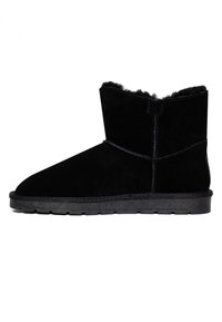 Stivali alla caviglia in suede nero con una morbida fodera pelosa, punta arrotondata e suola in gomma. Presentano cuciture lungo le cuciture e un design a profilo basso.