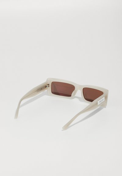 Lunettes de soleil à monture rectangulaire beige avec verres marron et logo de la marque visible sur la branche droite.