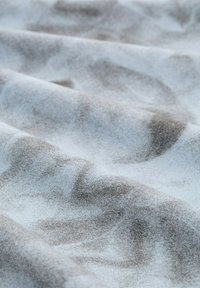 Textilný materiál s jemnou textúrou a abstraktnými vzormi v odtieňoch šedej a hnedej na svetlomodrom pozadí, ktorý predvádza vlnivý záves.