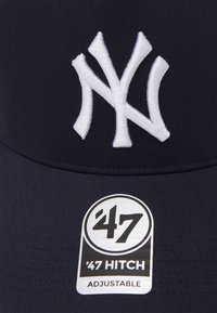 Căciulă de baseball de marină, cu logo-ul alb brodat "NY", curea ajustabilă și etichetă '47 Hitch alb-negru atașată.