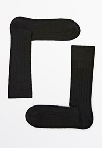 Calze nere a coste disposte a forma di quadrato, caratterizzate da una texture morbida e aree della punta e del tallone rinforzate per una maggiore durata.
