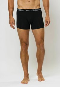 Črne boksarice iz bombaža, z elastičnim pasom z blagovno znamko z oznako "U.S. POLO ASSN.", gladko teksturo in prilegajočo obliko.