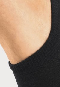 Schwarze Knöchelsocke aus strukturiertem Stoff, mit einem gerippten Bund und einem sichtbaren Abschnitt nackter Haut am Knöchel.