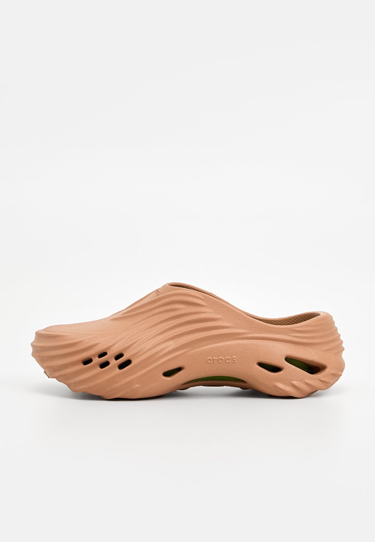Scarpa slip-on in marrone chiaro, realizzata in materiale testurizzato con design ondulato. Presenta fori di ventilazione e un interno imbottito per il massimo comfort.