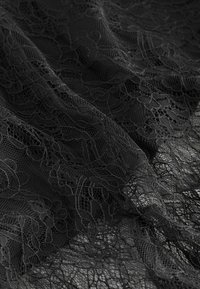 Schwarzer Spitzenstoff mit feinen Blumenmustern und zarten Texturen. Das Material ist transparent, mit feinen Fäden, die einen Überlappungseffekt erzeugen.