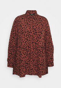 Rotes Hemd mit einem schwarz gepunkteten Muster, Knopfleiste, Kragen und geraffter Taille. Lange Ärmel mit geknöpften Manschetten.