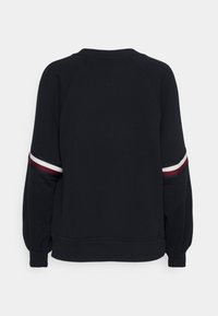 Felpa nera con maniche a raglan, caratterizzata da righe bordeaux, bianche e blu navy sui polsini. Tessuto morbido con una texture liscia.