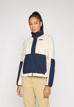 Veste en polaire crème et marine ; dotée d'un col montant, d'une fermeture éclair frontale, de poignets élastiques et de poches latérales ; marquée d'un logo sur la poitrine.