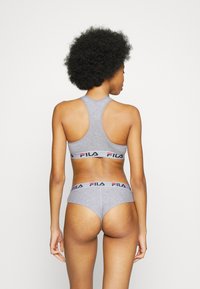 Sivi sportski grudnjak i odgovarajući gaćice s bikini krojem s bendom s Fila logotipom. Glatki pamučni materijal, dizajn s racerback leđima, minimalistički stil.