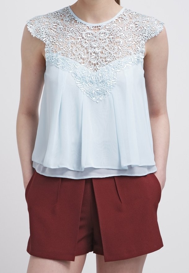 Vaaleansininen yläosa, jossa on pitsiyksityiskohtia kukkakuviolla, yhdistettynä burgundinpunaisiin korkeavyötäröisiin shortseihin, joissa on edessä poimutuksia.