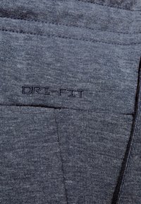 Graues Dri-Fit-Sportgewebe mit strukturiertem Muster, bestickt mit "DRI-FIT"-Branding, glatte Oberfläche und dehnbare Zusammensetzung.