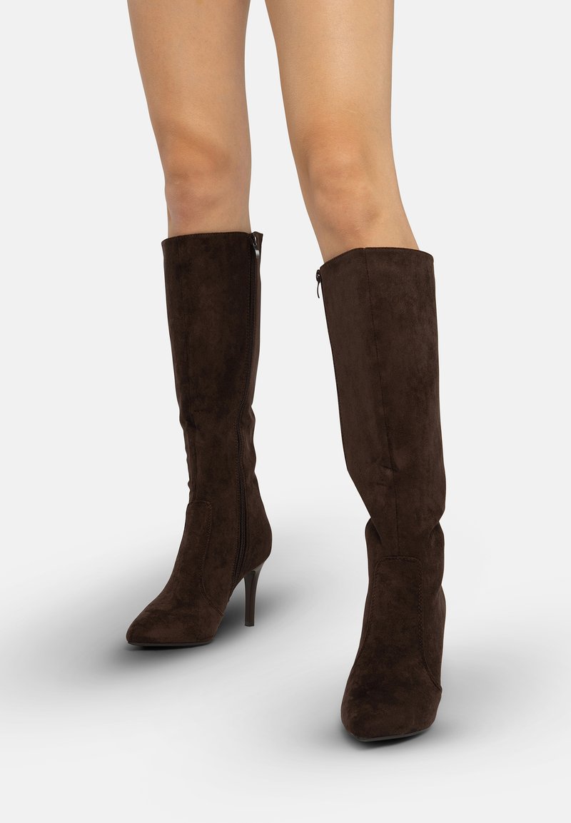 Botas hasta la rodilla de ante marrón con punta puntiaguda y tacón alto. Incluyen una cremallera lateral y una textura suave.