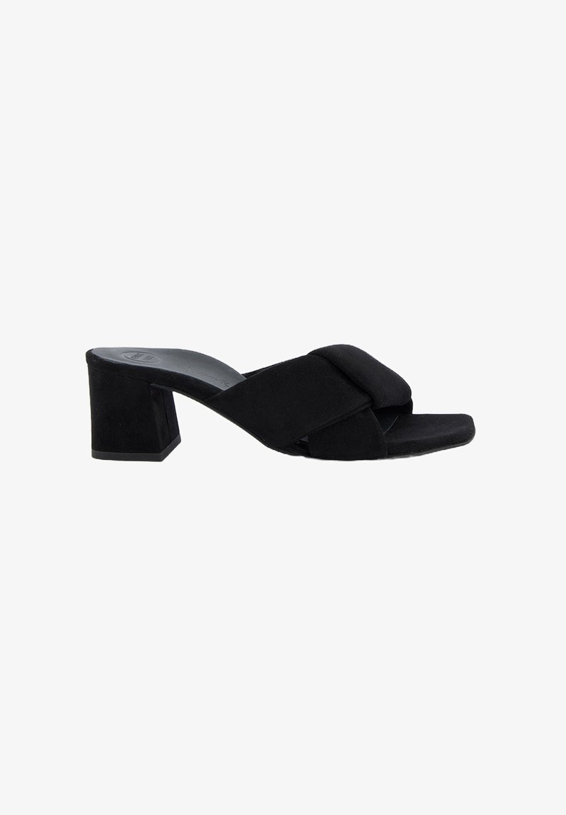 Des mules en suède noir à talon bloc présentent un bout ouvert et un design de brides croisées. Le talon a une forme carrée et mesure environ 5 cm.