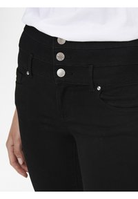Jeans de mezclilla negra con una cintura alta, cuatro botones plateados, bolsillos frontales y un acabado de textura suave.