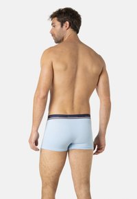 Boxers en bleu clair avec une ceinture bleu marine portant le nom de la marque. Tissu lisse, design ajusté et longueur mi-cuisse.