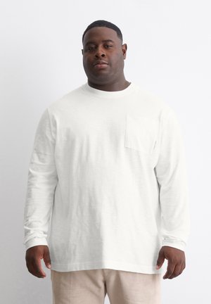 Langarmiges weißes T-Shirt aus weichem Material, mit einer Brusttasche, rundem Ausschnitt und lockerer Passform. Strukturierte Oberfläche.