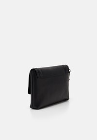 Sac à main en cuir noir avec une surface texturée, dotée d'un rabat pliable et de détails de coutures discrets. Forme rectangulaire compacte.