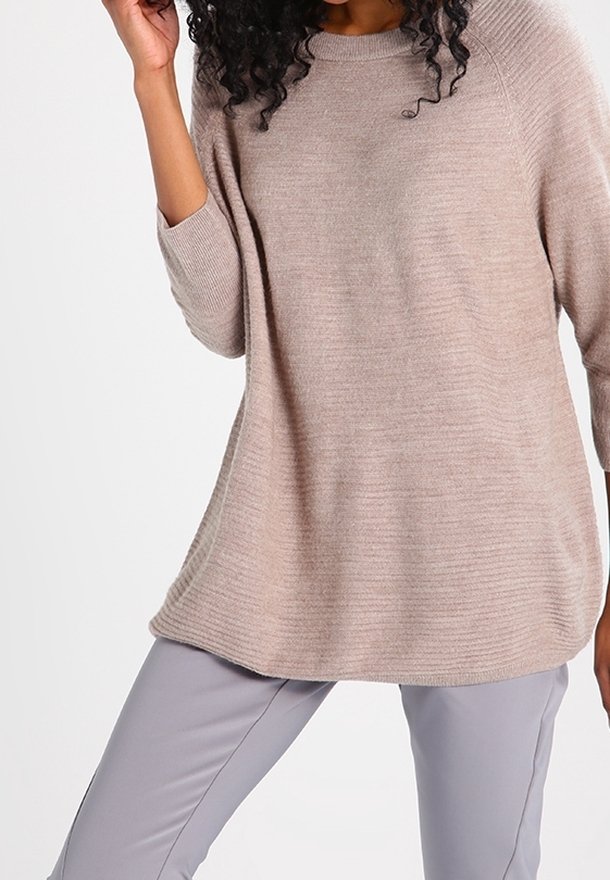 Pull beige clair en maille avec une coupe décontractée, manches raglan et ourlet côtelé. Associé à un pantalon slim gris clair.