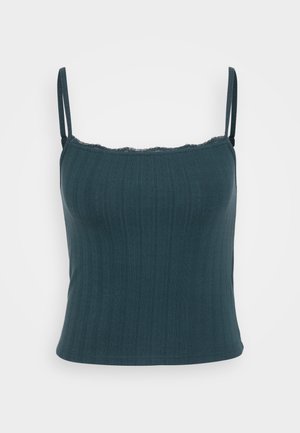 Top a maniche sottili in teal scuro con spalline regolabili, texture a coste e rifinitura in pizzo a scallop lungo lo scollo. Fit elegante e sartoriale.