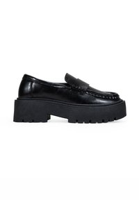 Mocasines de cuero negro con suela de goma gruesa, que presentan un detalle de costura y una correa ancha a lo largo del empeine.