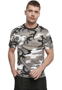 Kamufliažo marškinėliai pilkos, baltos ir juodos spalvos, su apvalia iškirpte, trumpomis rankovėmis ir laisvu siluetu, pagaminti iš minkštos medvilnės medžiagos.