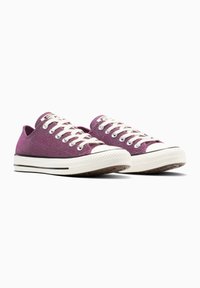 Sneakers di tela viola glitter con lacci bianchi, punta in gomma e una striscia nera attorno alla suola. Presentano un design a collo basso.