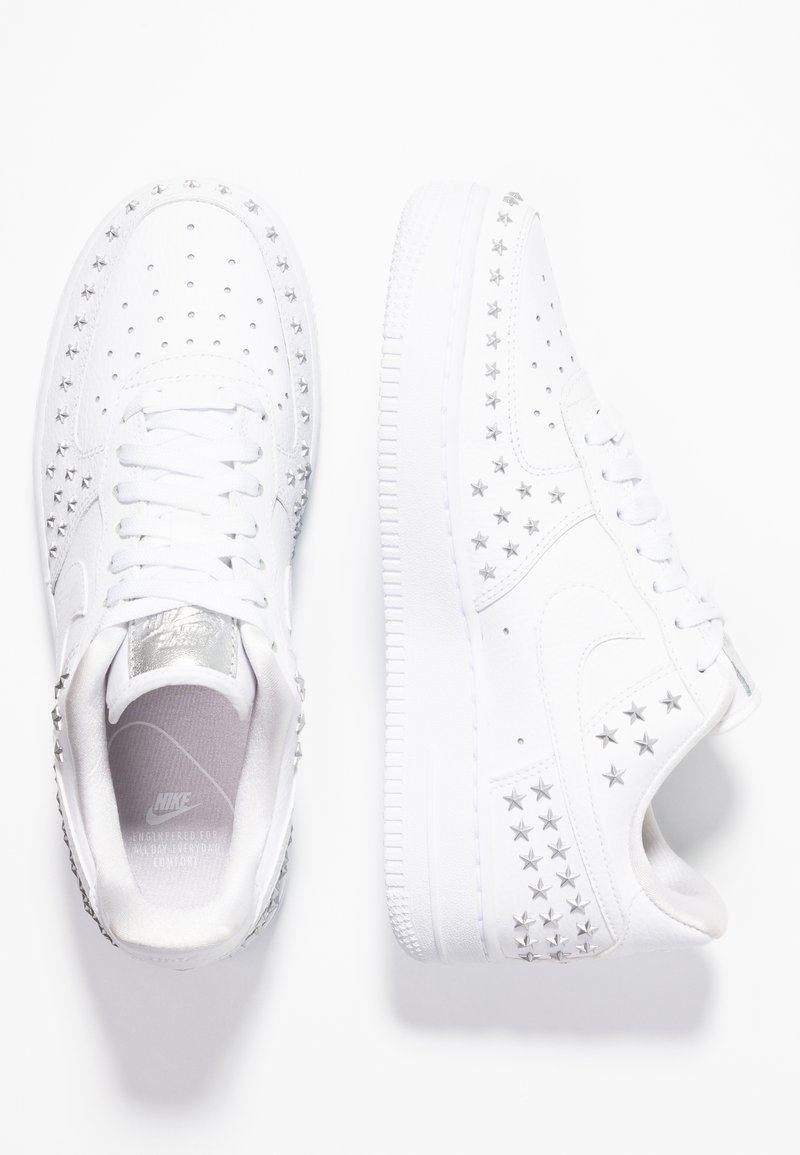 Weiße Leder Nike Air Force 1 Sneaker mit silbernen Sternen, durchlöchertem Zehenbereich und einer strukturierten weißen Gummisohle.