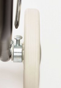 Primer plano de una rueda de goma blanca con una superficie texturizada, unida por un soporte de metal plateado y un tornillo a un marco de metal oscuro.