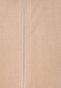 Beige fleece tyg med en mjuk textur, med ett centralt dragkedjeslut. Dragkedjan är i en ljus färg som kontrasterar med tyget.