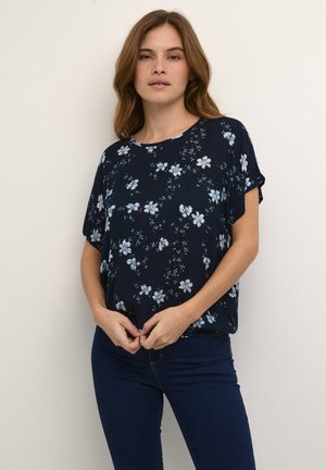 Blusa floreale in tessuto blu scuro con maniche corte, decorata con fiori bianchi e azzurri, con scollo rotondo e una vestibilità ampia.