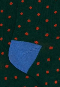 Calzini verdi con pois rossi, con un accento blu sul tallone. Realizzati in tessuto a maglia testurizzato.