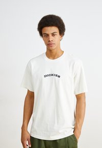 White cotton t-shirt featuring a black curved "DICKIES" logo on the chest. Short sleeves and a relaxed fit with a crew neckline.