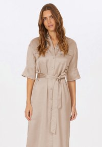 Beiges, knöpfbares Midi-Kleid mit kurzen, umgeschlagenen Ärmeln, einem Bindegürtel in der Taille und zwei Brusttaschen. Glattes, strukturiertes Gewebe.