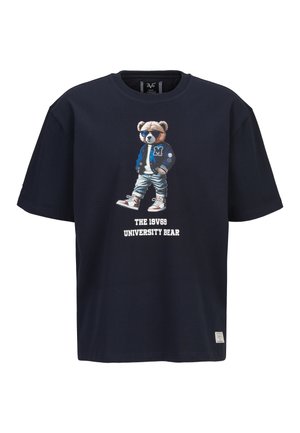 Marineblaues T-Shirt mit Grafik eines Bären mit Sonnenbrille, Collegejacke, Jeans, Sneakers und dem Text "THE 19V69 UNIVERSITY BEAR" darunter.