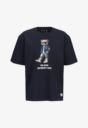 Donkerblauw T-shirt met afbeelding van een beer met een zonnebril, varsityjack, spijkerbroek, sneakers, en de tekst "THE 19V69 UNIVERSITY BEAR" eronder.