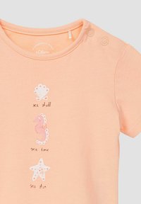 Pfirsichfarbene Babykleidung mit kurzen Ärmeln, zwei Schulterknöpfen und drei maritimen Drucken, die mit Muschel, Seepferdchen und Seestern beschriftet sind.