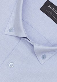 Jasnoniebieska slim-fit koszula z teksturowanej tkaniny, z kołnierzykiem w szpic i dwoma jasnoniebieskimi guzikami przy kołnierzyku. Metka głosi "BORGO."