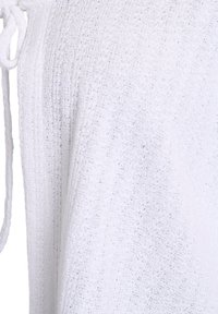 Top bianco in maglia con una vestibilità ampia, caratterizzato da un motivo testurizzato e un dettaglio con fiocco sul colletto. Tessuto morbido, design leggero.
