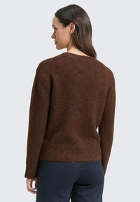 Brauner Strickpullover mit strukturierter Oberfläche, rundem Ausschnitt und langen Ärmeln. Er hat eine lockere Passform und einen gerippten Saum.
