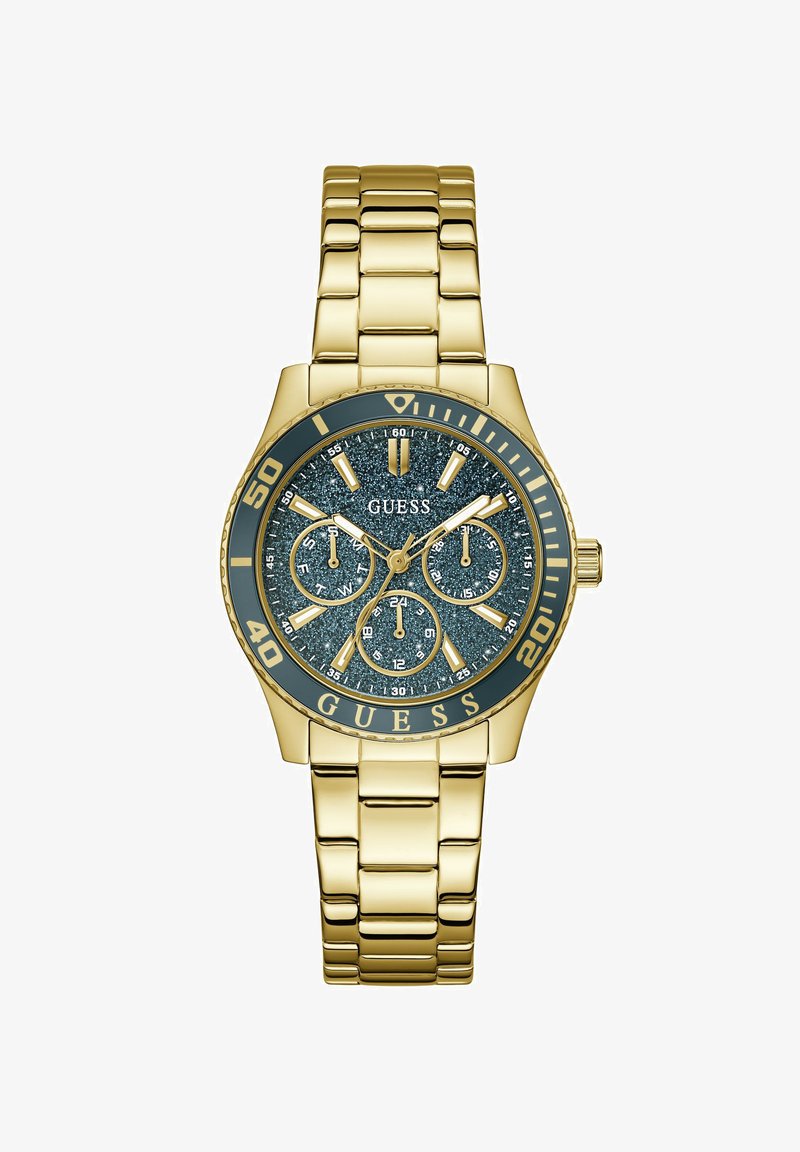 Ρολόι χειρός Guess με χρυσή απόχρωση, καντράν σκούρο μπλε με γκλίτερ, τρεις υποκαντράν, φωσφορίζοντες δείκτες και βραχιόλι από μεταλλικούς κρίκους στον ίδιο τόνο.