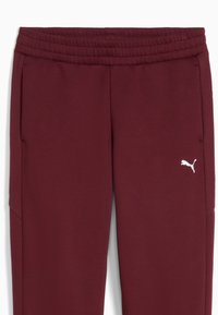 Pantalones de chándal color burdeos con una cinturilla acanalada, bolsillos laterales y un pequeño logo blanco de Puma en el muslo izquierdo. Tejido suave y texturizado.