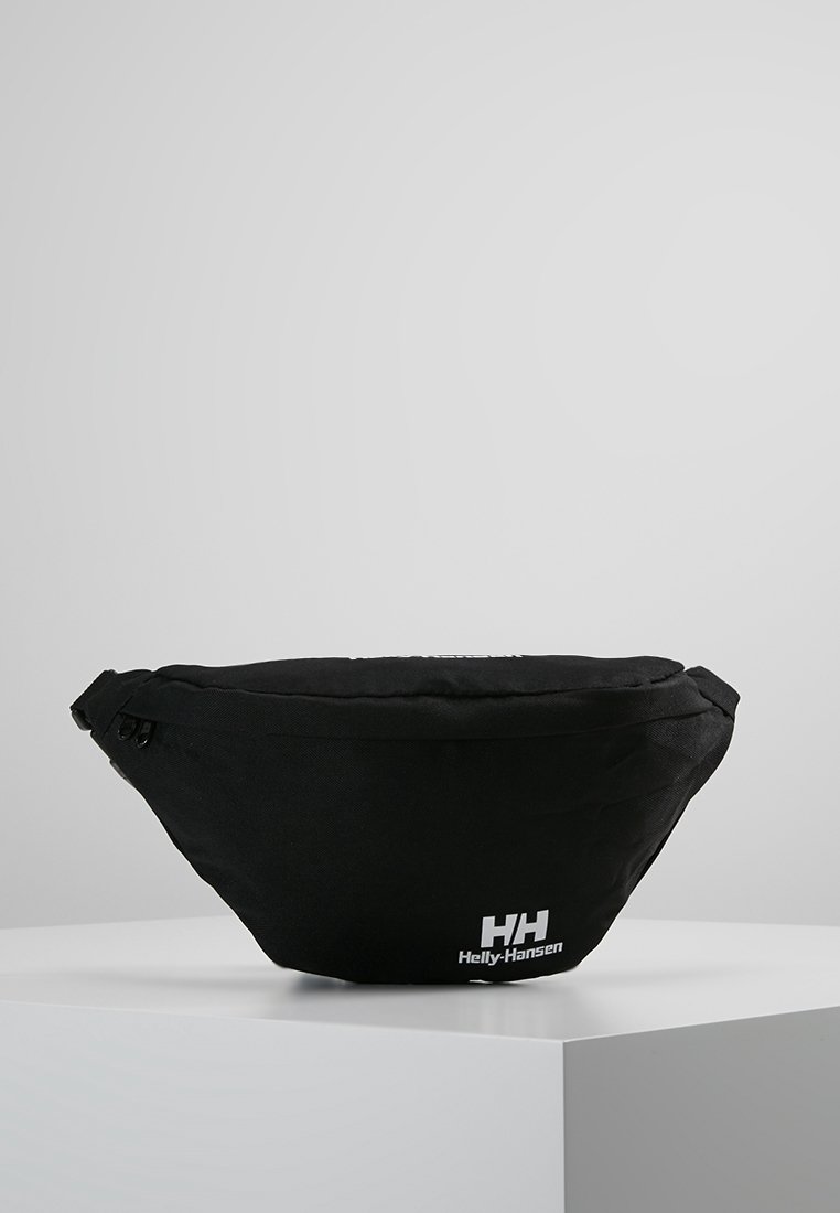 Banane noire en tissu résistant, dotée d'un design arrondi, d'une fermeture éclair et d'un logo Helly Hansen blanc à l'avant.