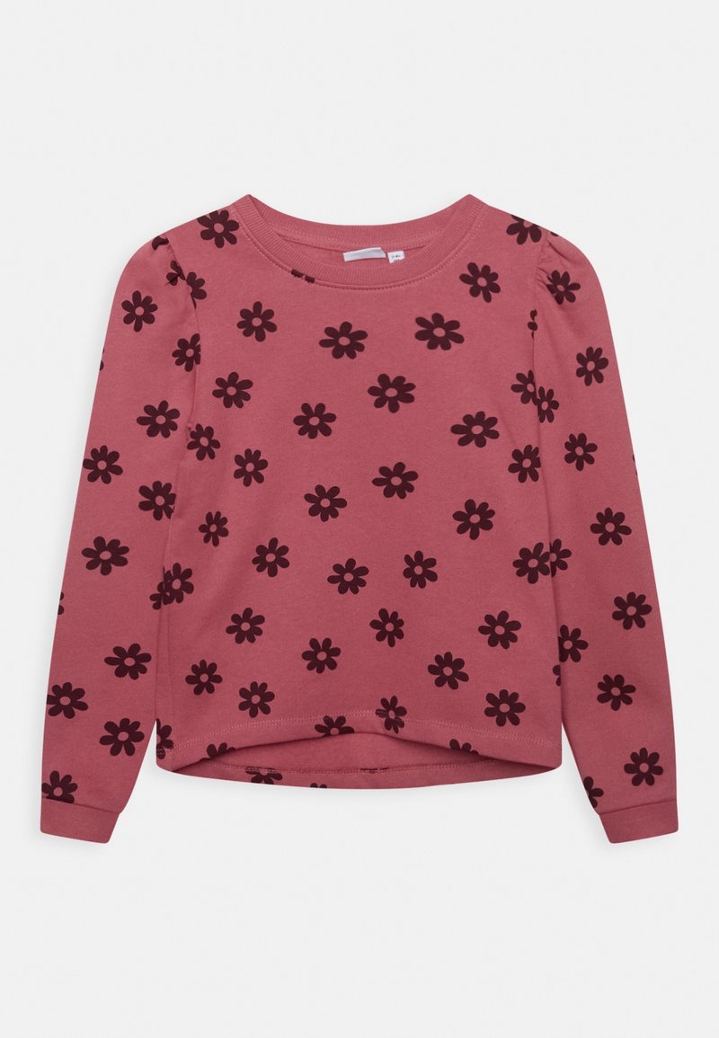 Haut à manches longues en tissu rose présentant un motif floral foncé répété, un col rond, et un ourlet légèrement arrondi. Texture douce.