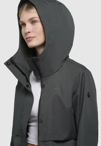 Korte zwarte jas met een capuchon en ritsluiting. Gemaakt van glad, waterafstotend materiaal. Voorzien van knopen en een logo-accent.