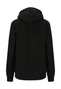 Musta huppari näkyy takaa, jossa on pitkät hihat, röyhelöhiha ja istuva helma valkoista taustaa vasten.