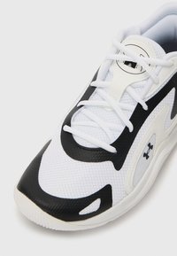 White athletic shoe featuring a black mesh overlay, structured sole, rounded toe, and prominent branding detail on the side.