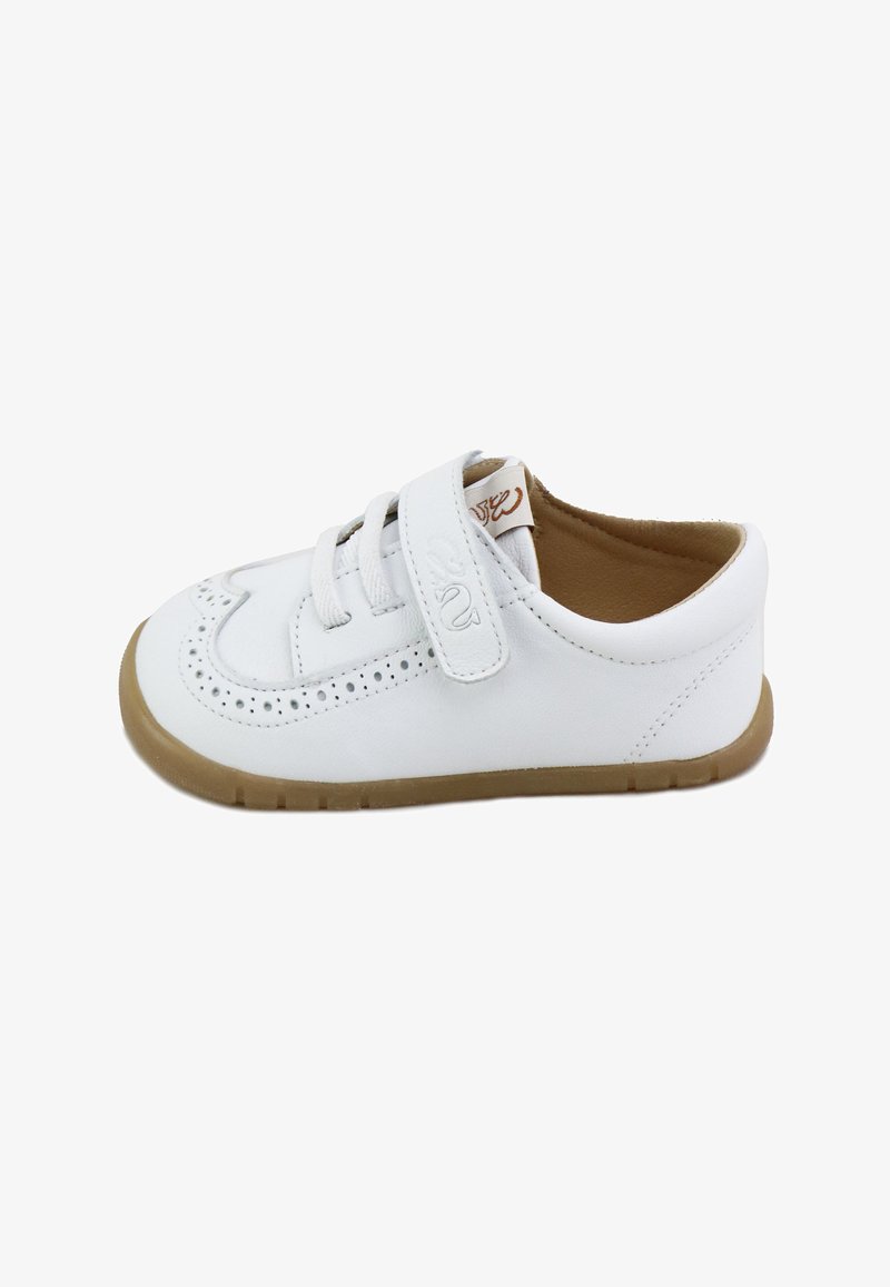 Zapato de cuero blanco para bebé con patrones decorativos perforados, correa de velcro, cordones y suela de goma marrón clara.