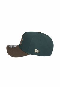 Casquette de baseball vert foncé avec une visière marron, ornée de broderies à l'avant et d'un logo sur le côté. Fabriquée en matériau textile.